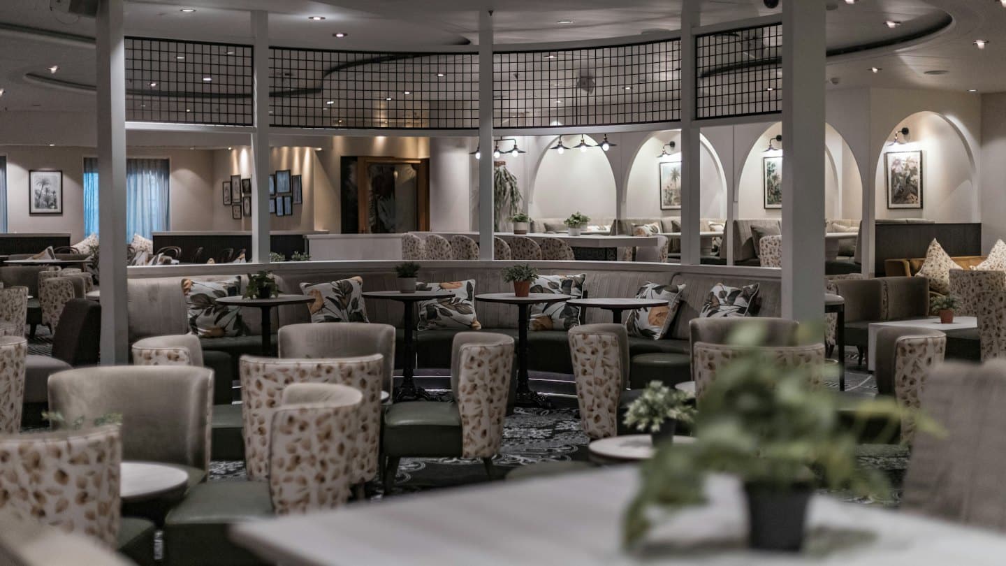 Elegante salón de hotel con asientos, mesas y plantas.