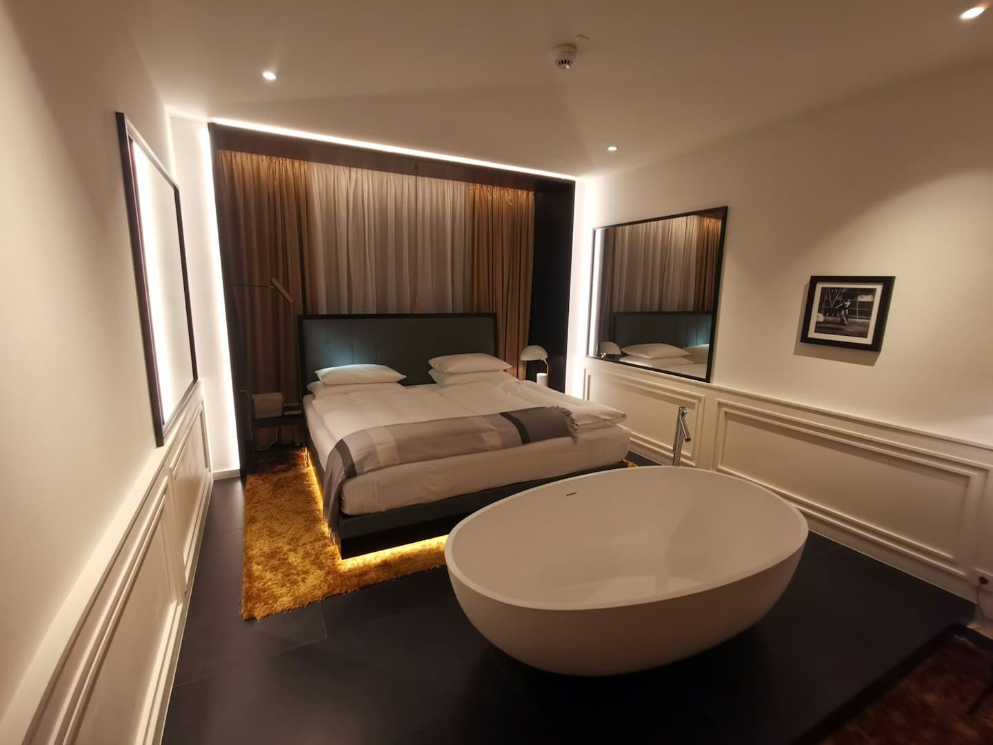 Habitación de hotel con cama king y bañera independiente.