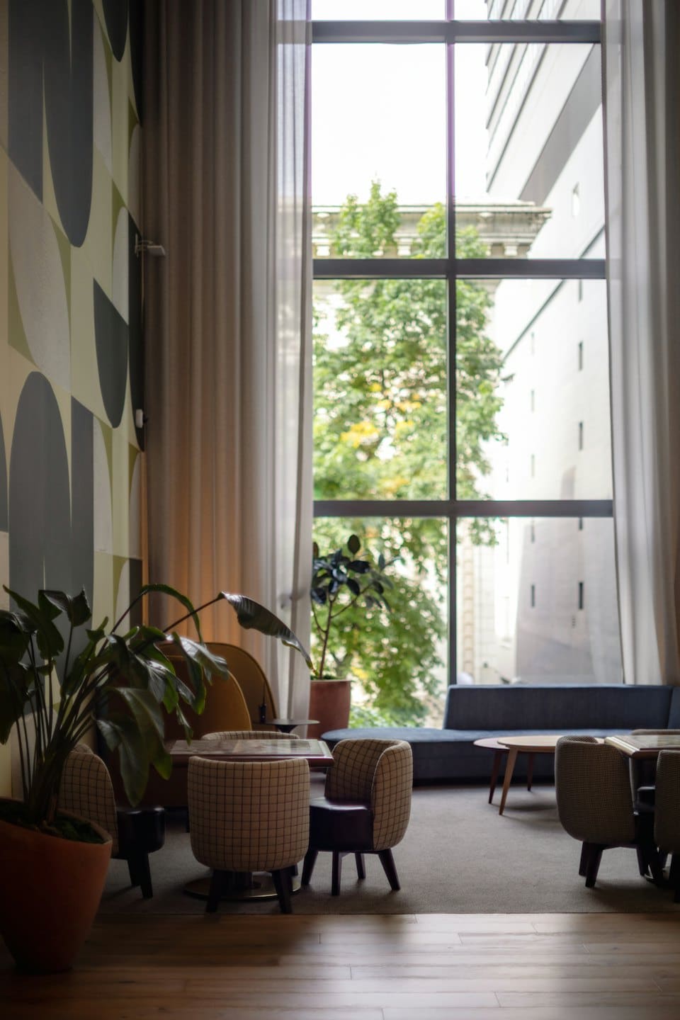 Lobby de hotel con sillones de cuadros y sofá azul junto a la ventana.