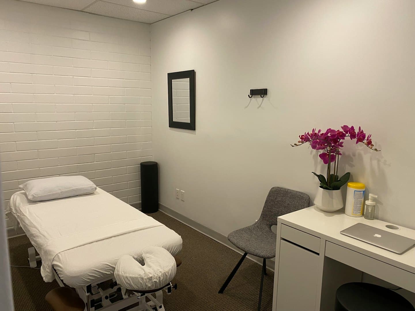 Sala de terapia con camilla, silla y escritorio.